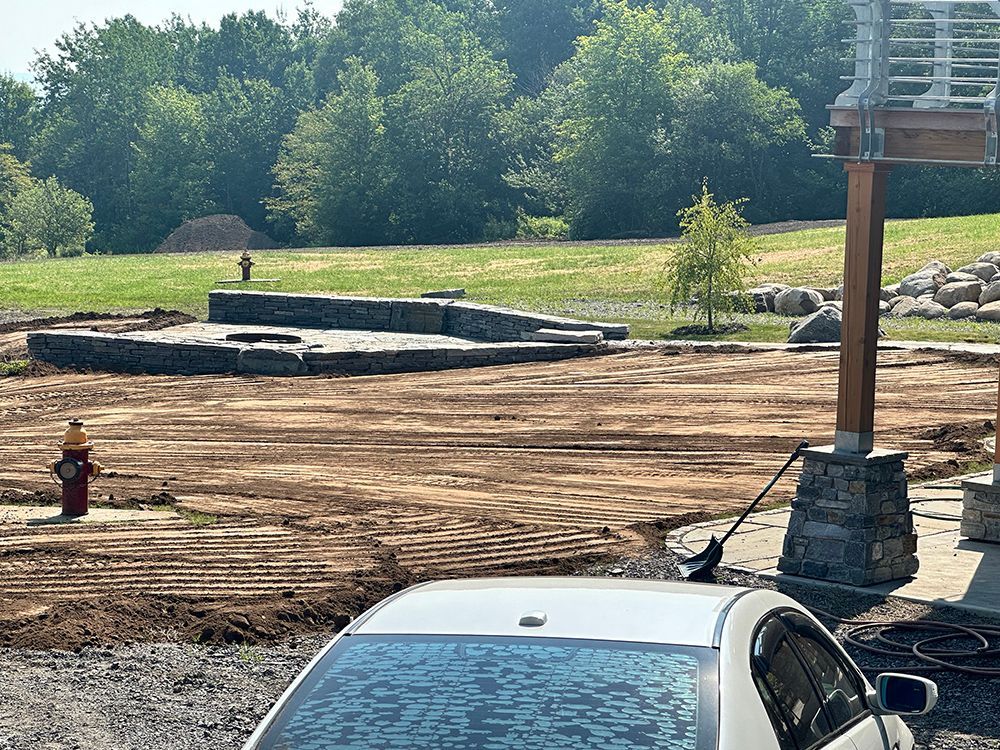 A white car is parked in a dirt field next to a fire hydrant.