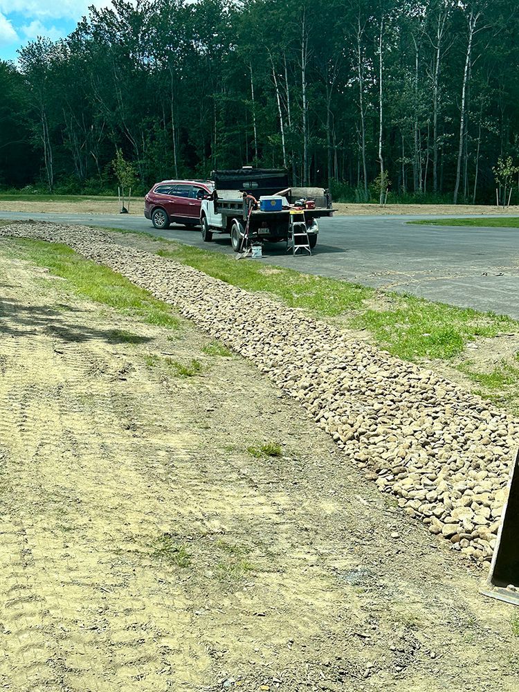 A truck is parked on the side of the road next to a gravel road.