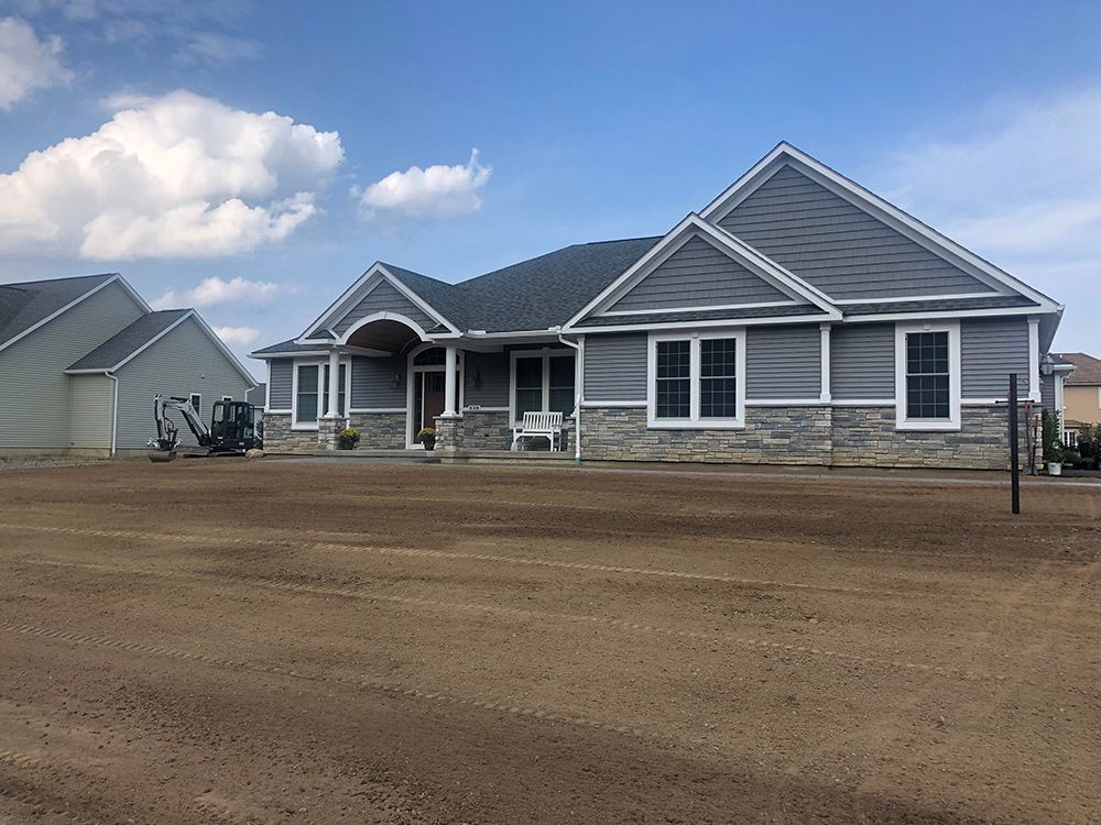 A large house is sitting in the middle of a dirt field.