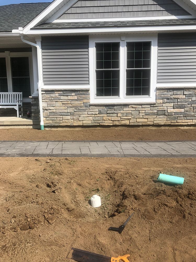 A house with a lot of dirt in front of it and a saw in the dirt.