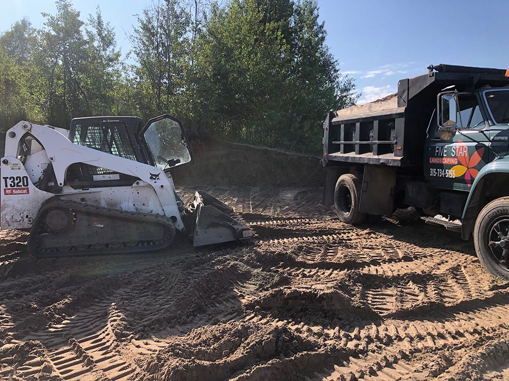 A bulldozer is moving dirt next to a dump truck.