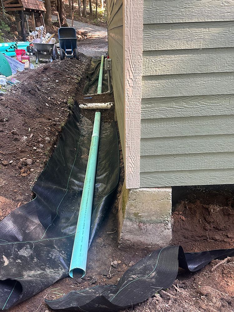 A green pipe is sitting in the dirt next to a house.