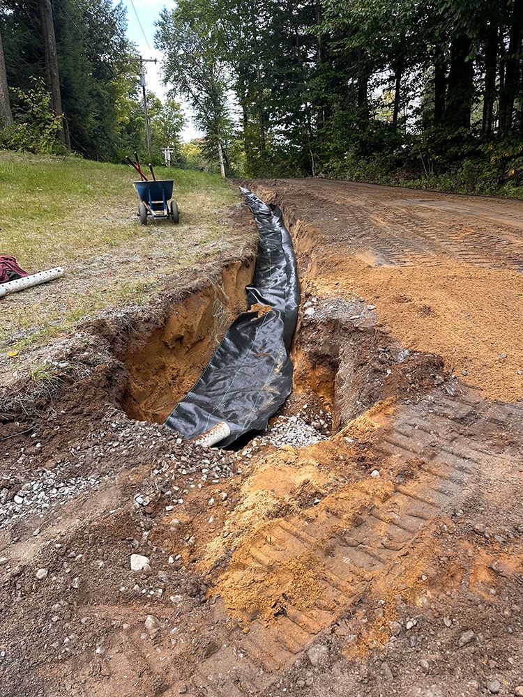 A large hole in the ground with a wheelbarrow in the background.