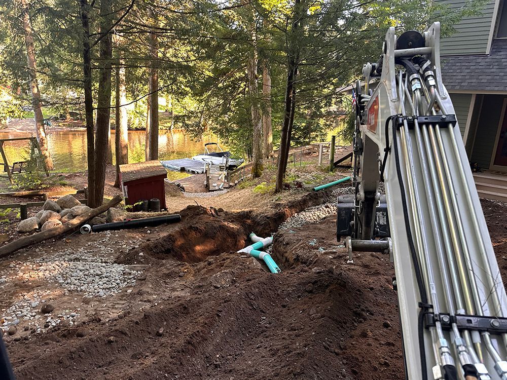 A large excavator is digging a hole in the dirt in front of a house.