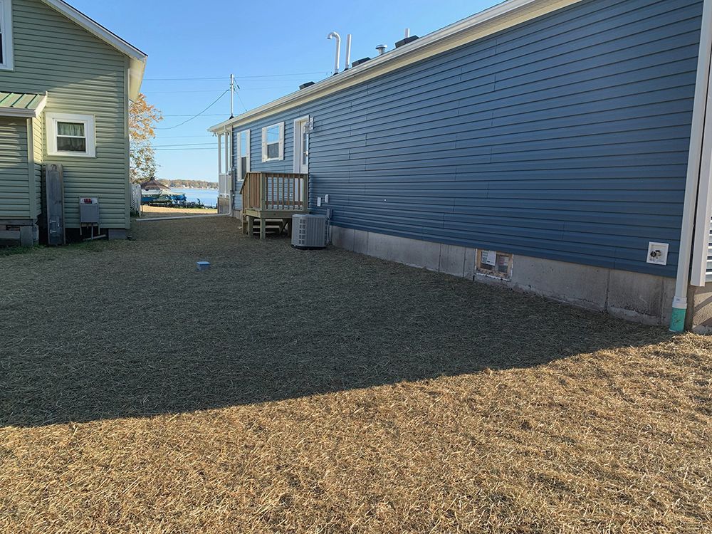 A house with a blue siding and a gravel driveway in front of it.