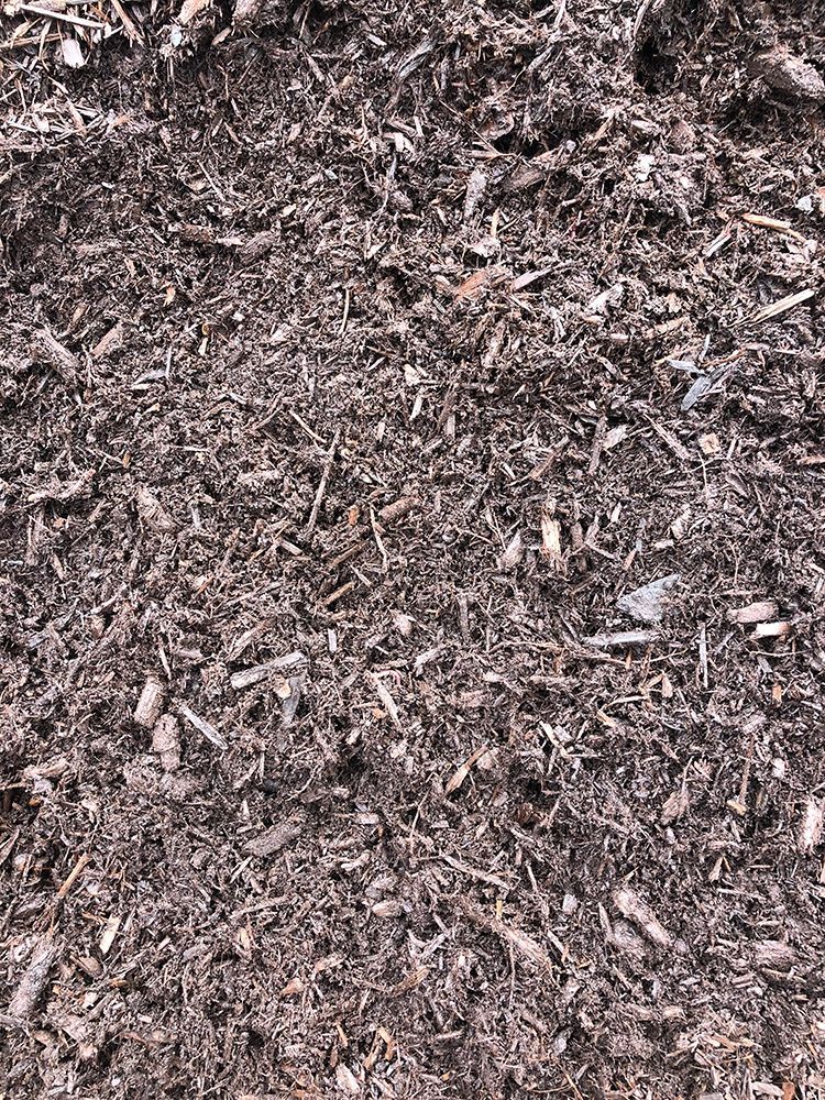 A pile of brown mulch is sitting on the ground.
