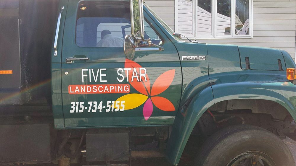 A five star landscaping truck is parked in front of a house