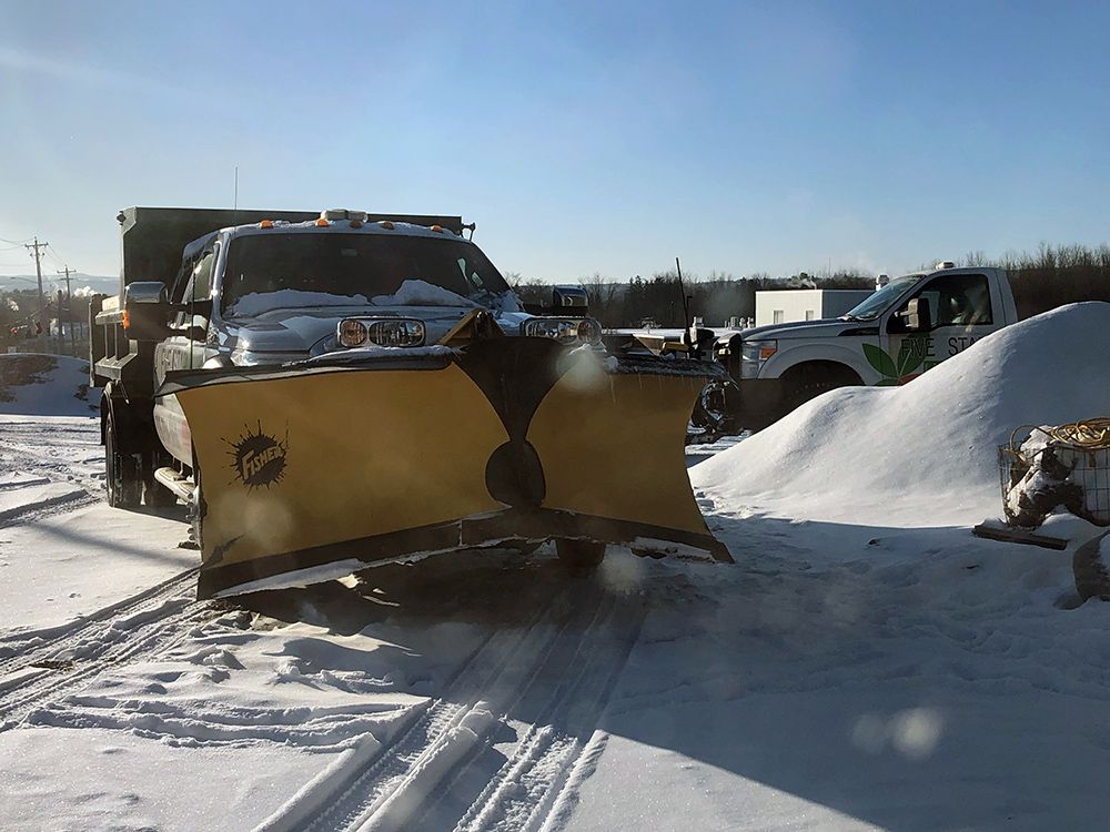 A snow plow is plowing snow on a snowy road