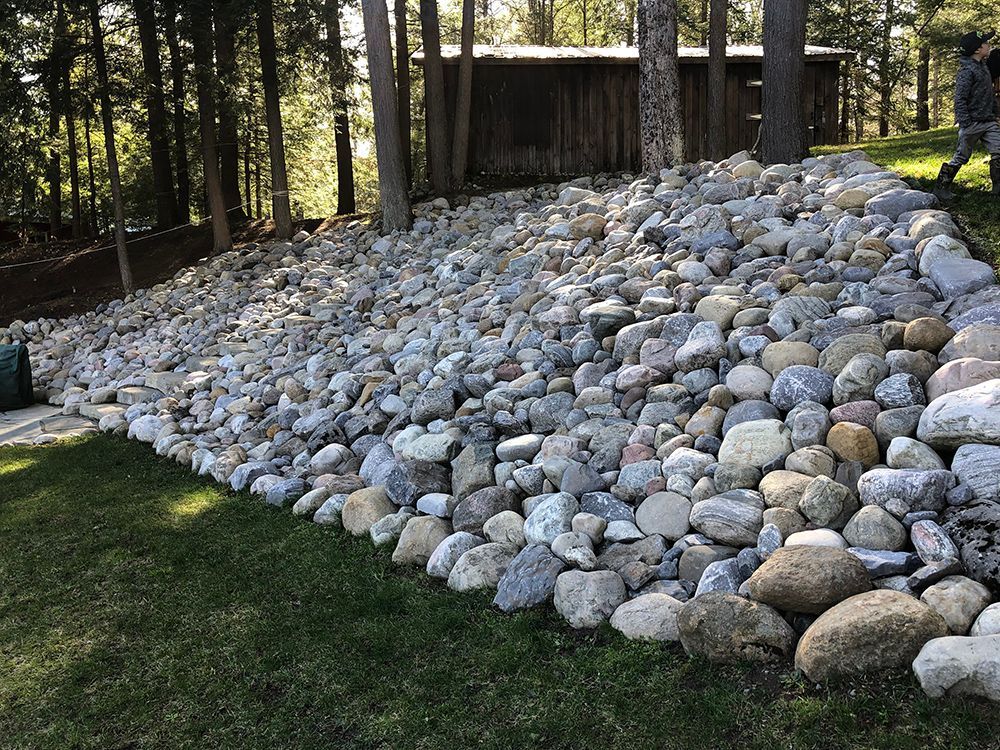 A large pile of rocks is sitting on top of a lush green lawn.