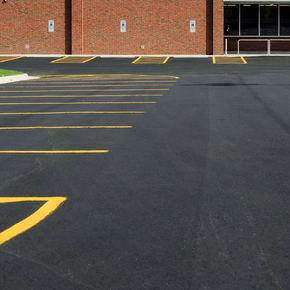 A parking lot with yellow lines and a brick building in the background