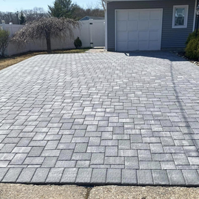 A brick driveway with a garage in the background