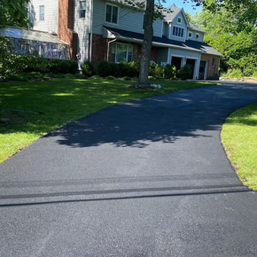 A black driveway leading to a large house