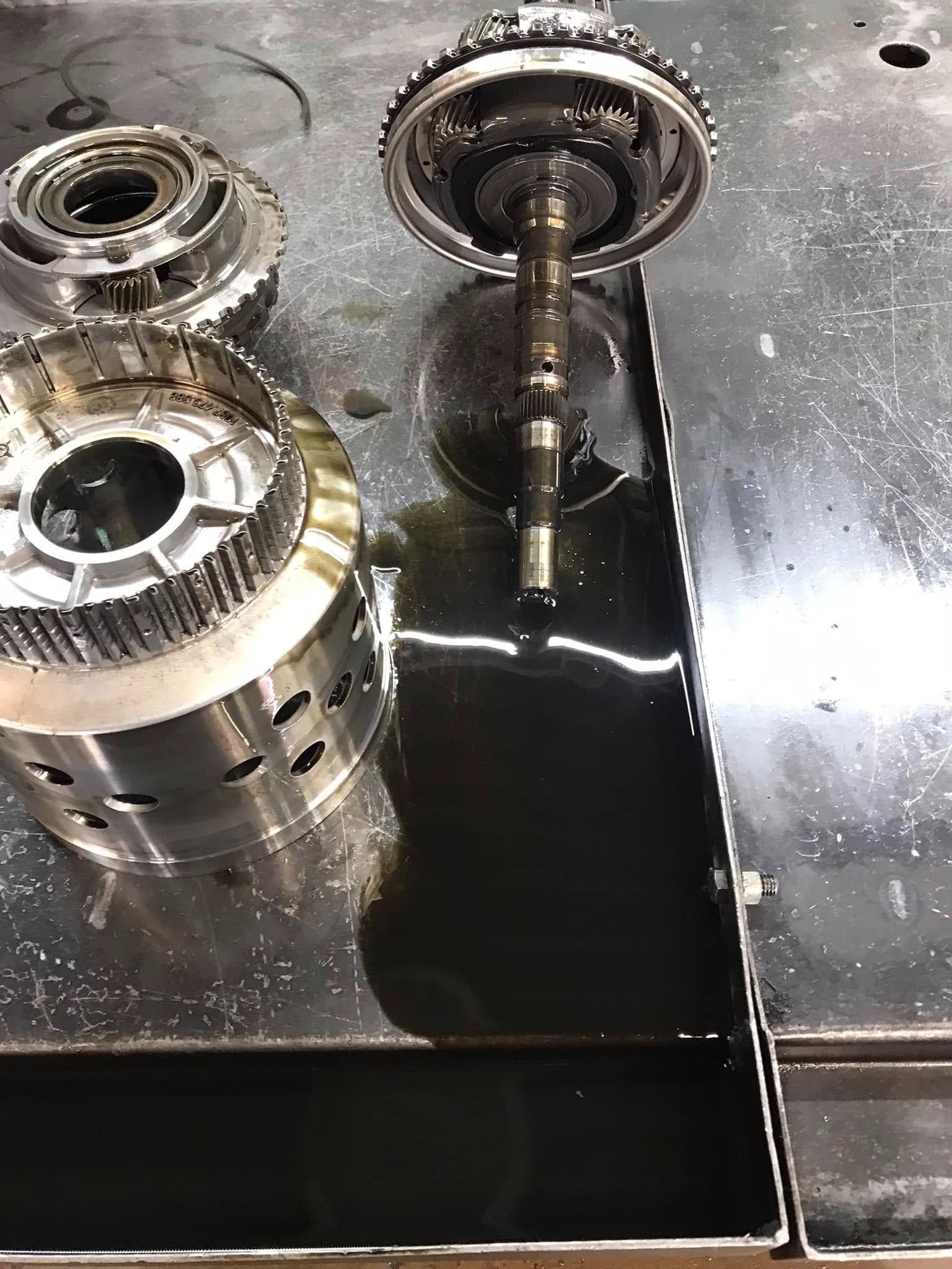 Transmission parts on a metal surface, with spilled dark oil.