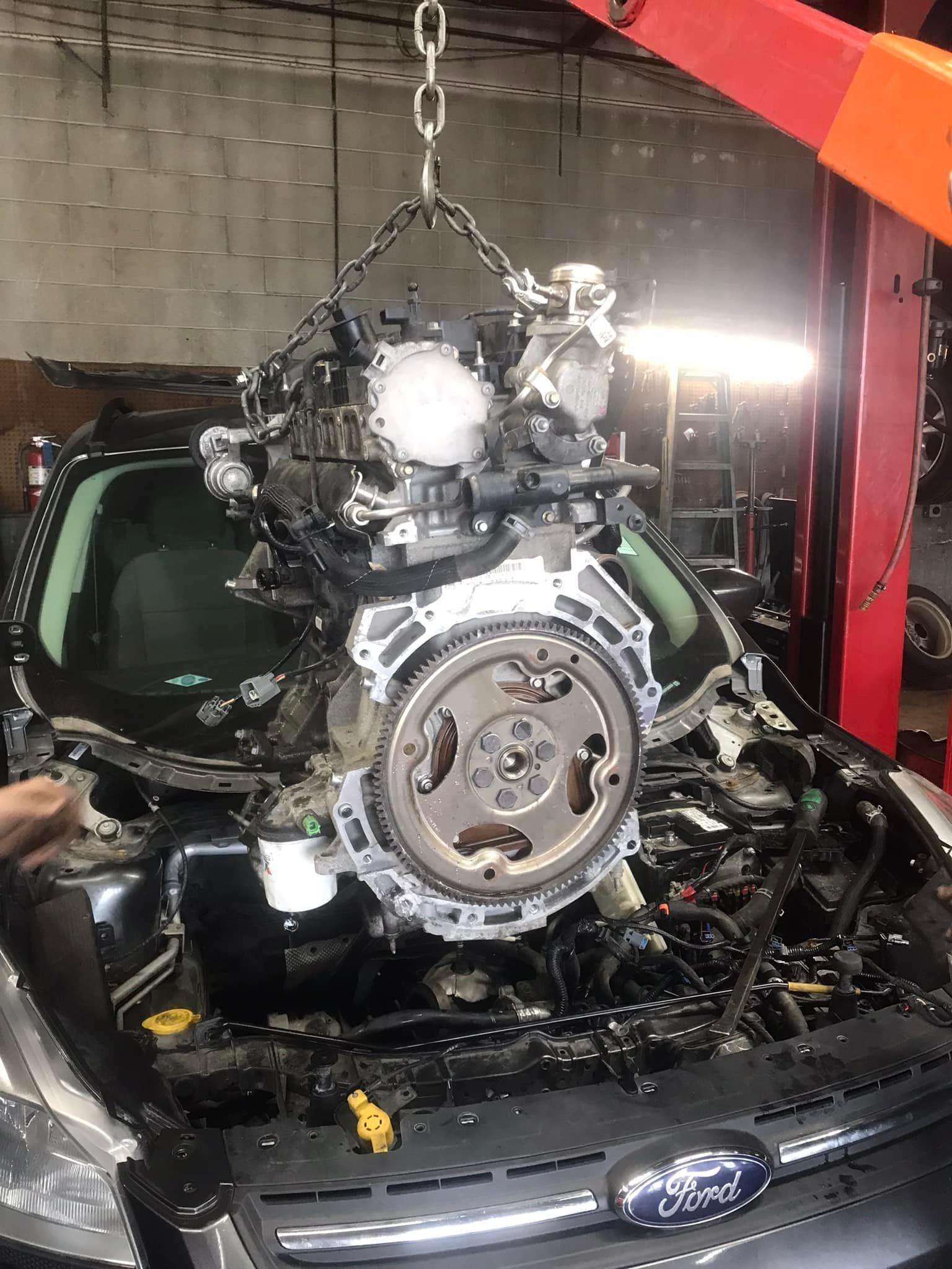 An engine being lifted from a car by a hoist in a garage.