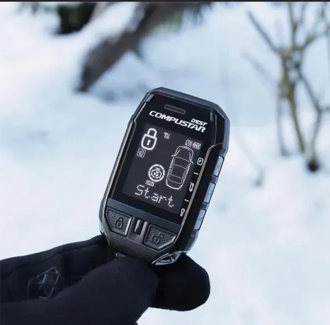 A person is holding a compustar car starter in their hand.