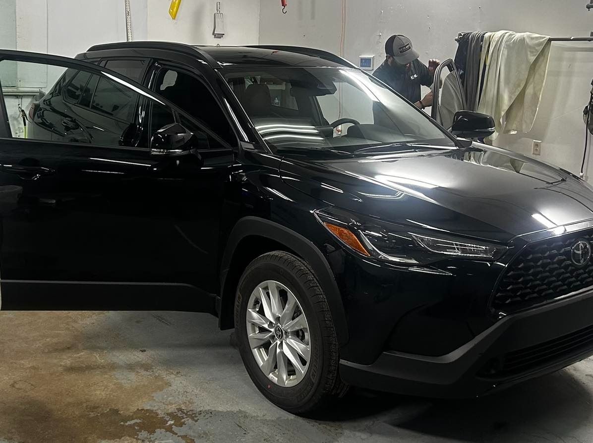 A black car is parked in a garage with its doors open.
