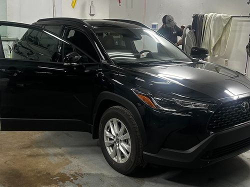 A black car is parked in a garage with its doors open.