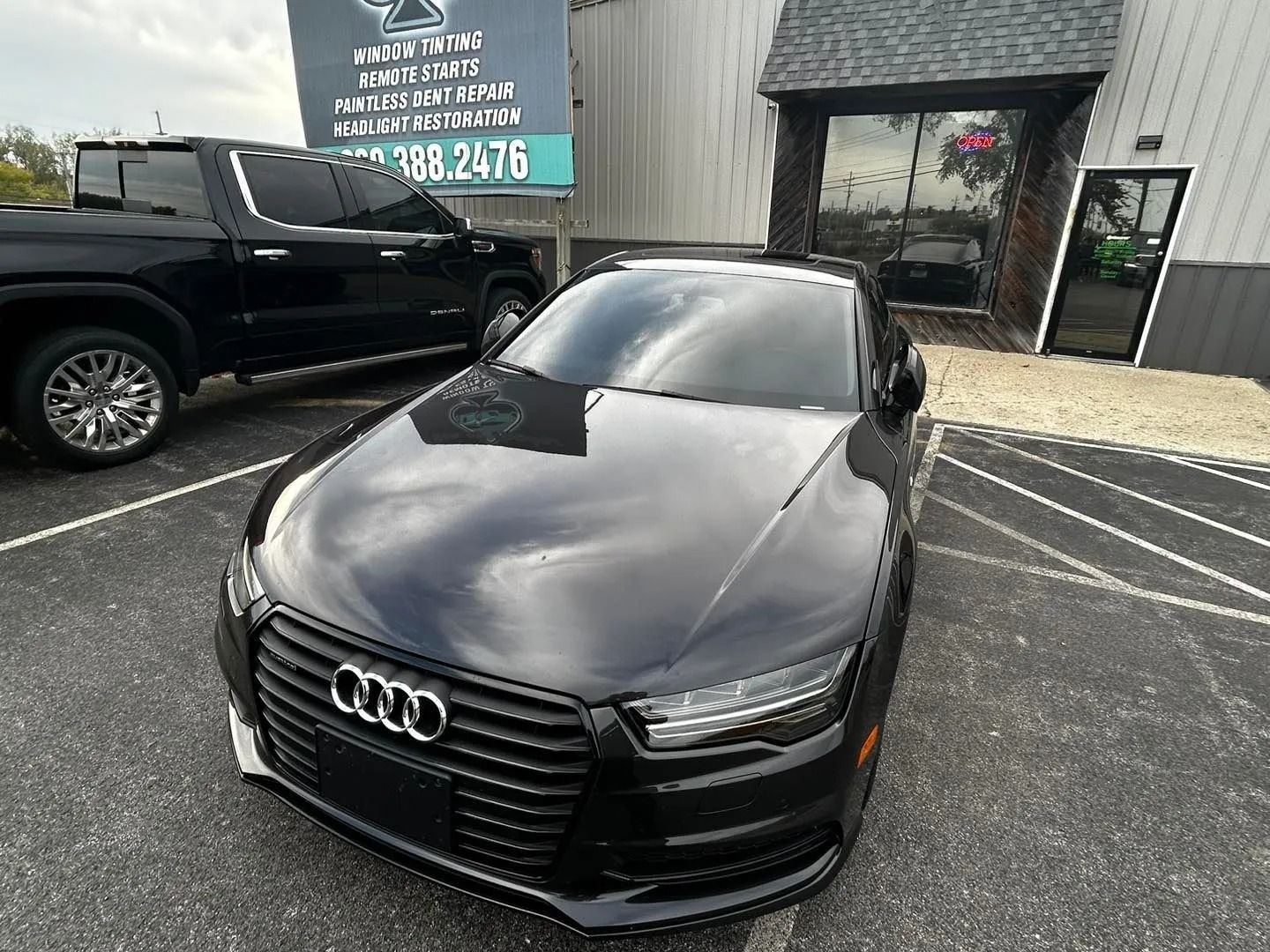 A black Audi a7 is parked in front of a building.