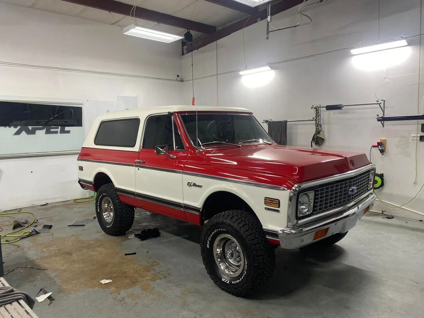 A red and white truck is parked in a garage.
