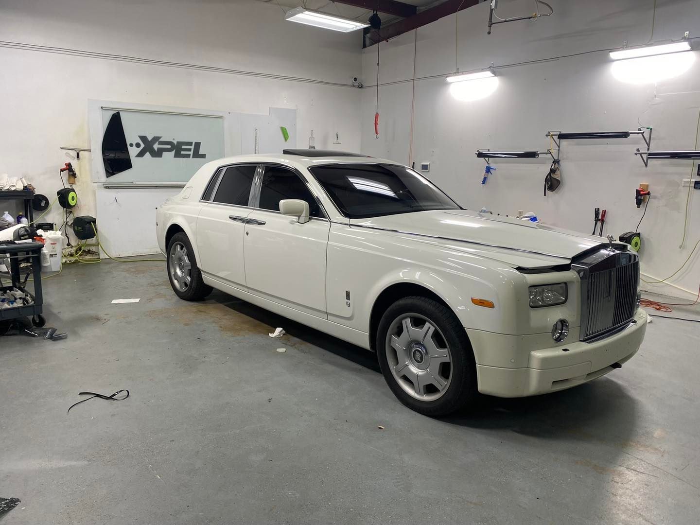 A white Rolls-Royce Phantom is parked in a garage.