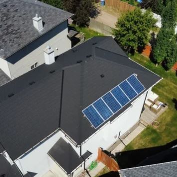 An aerial view of a house with solar panels on the roof.