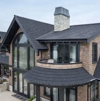 An aerial view of a large brick house with a black roof.