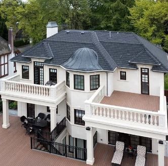 An aerial view of a large white house with a black roof.