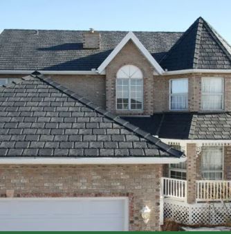 A large brick house with a black roof and a white garage door.