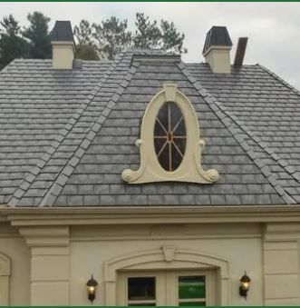 A house with a slate roof and a window on top