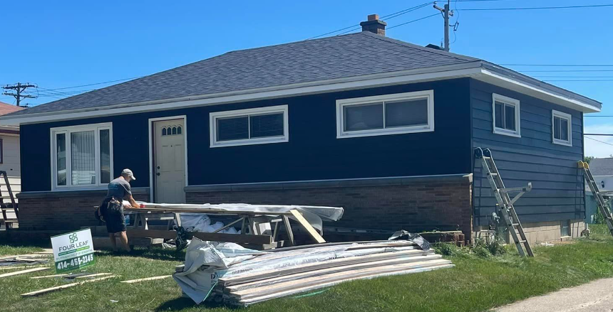 A man is standing in front of a house that is being remodeled.