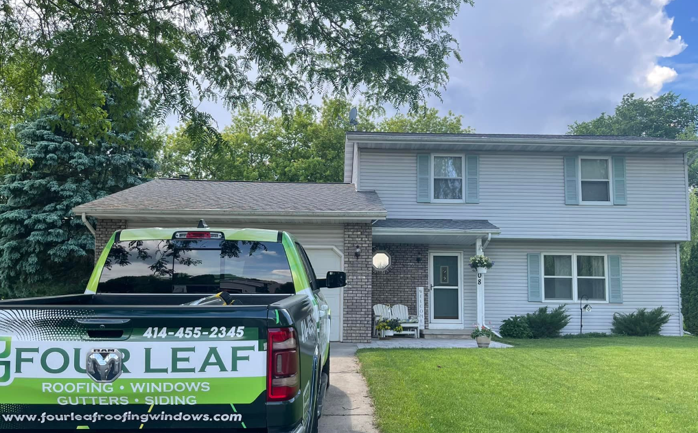 A four leaf truck is parked in front of a house.