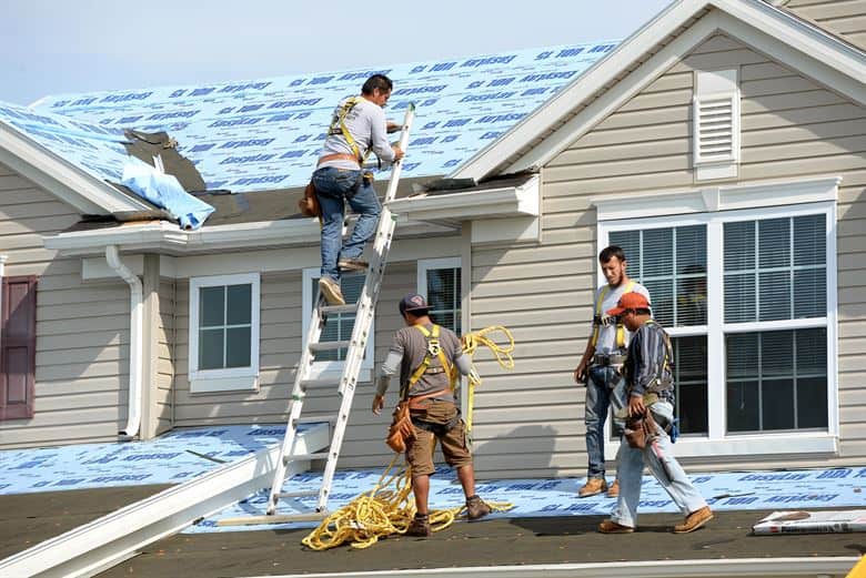 A group of men are working on the roof of a house.