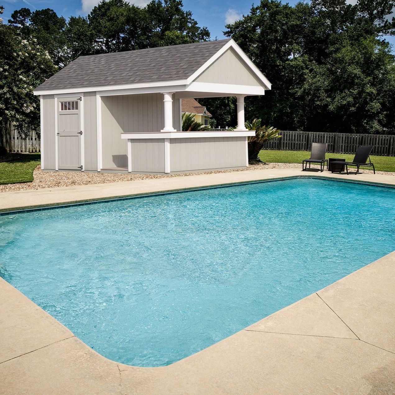 Backyard pool with a white cabana and lounge chairs on a sunny day