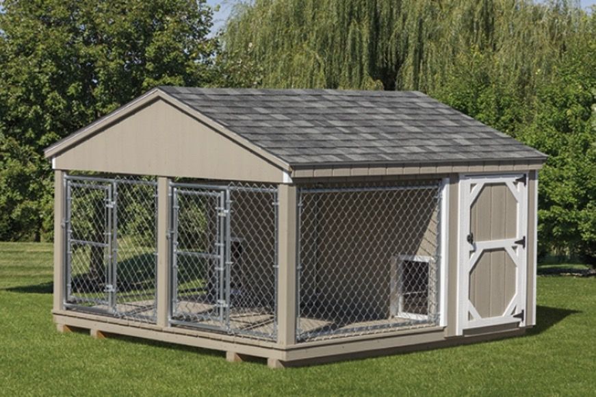 Outdoor wooden chain-link dog kennel with a sloped roof and fenced run on grass