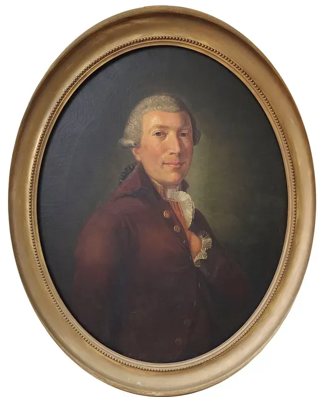 A portrait of a person wearing a formal burgundy coat and white cravat, set within an oval gold frame against a dark background.