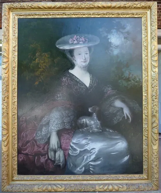 A woman in a dark lace gown and hat sits with a small dog in her lap, set against a hazy, dark landscape.