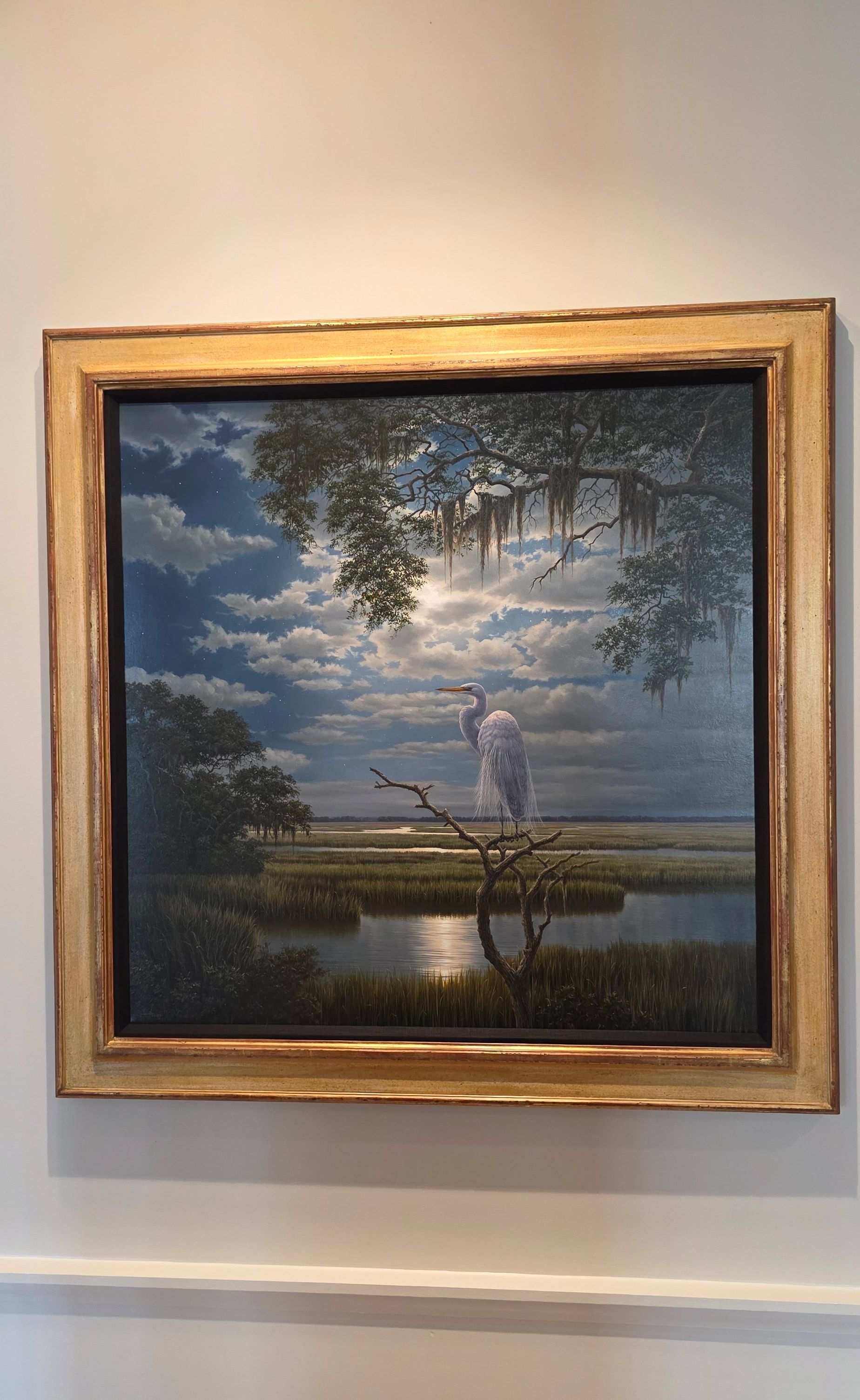 Framed landscape painting of a moonlit riverside with trees and a small boat on the water