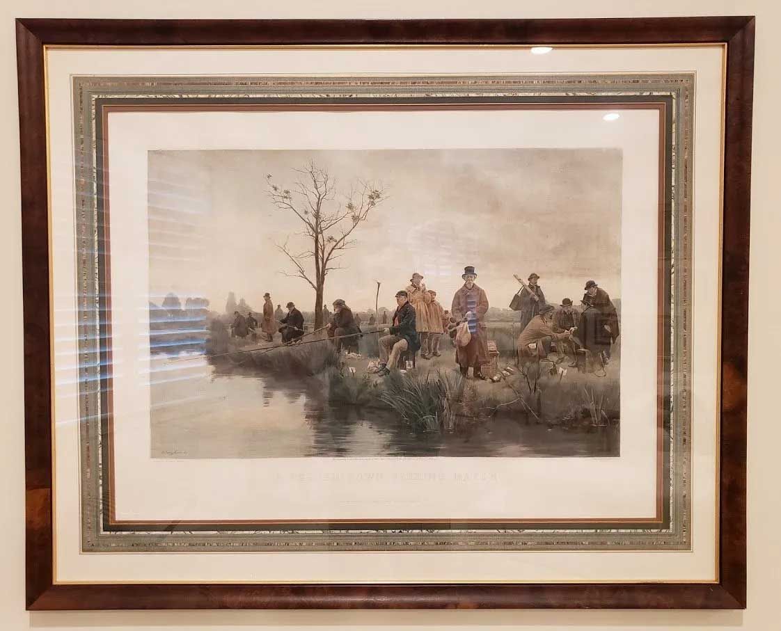 Framed print of a group of people fishing along a riverbank near a sparse, leafless tree under a muted, overcast sky.