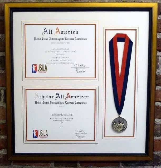 A framed display containing two USILA awards and a medal with a red and blue ribbon.