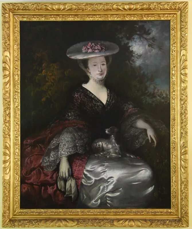 A portrait of a person in a wide-brimmed hat, lace sleeves, and a dark gown, holding a small dog in an outdoor setting.