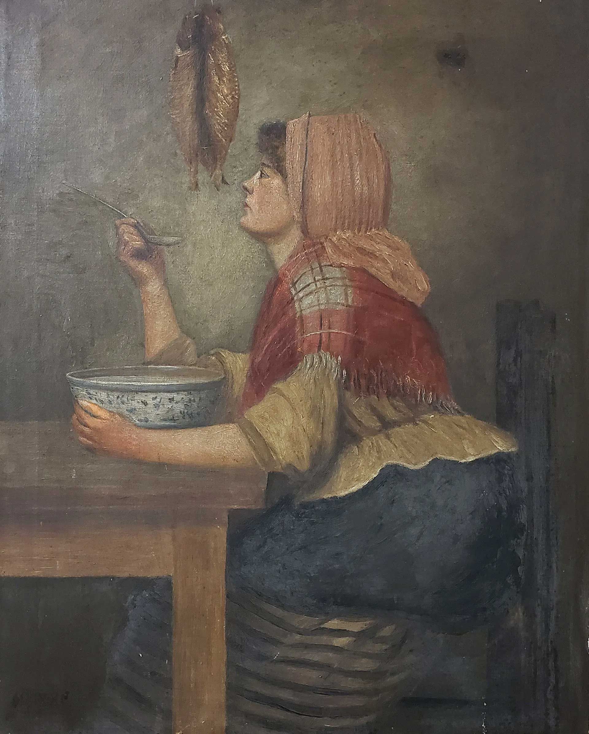 A person in a red shawl sits at a wooden table, looking up at two hanging birds, holding a bowl in one hand.