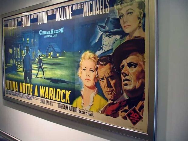 Framed Italian movie poster for "Warlock," featuring illustrations of the cast and a western town scene.