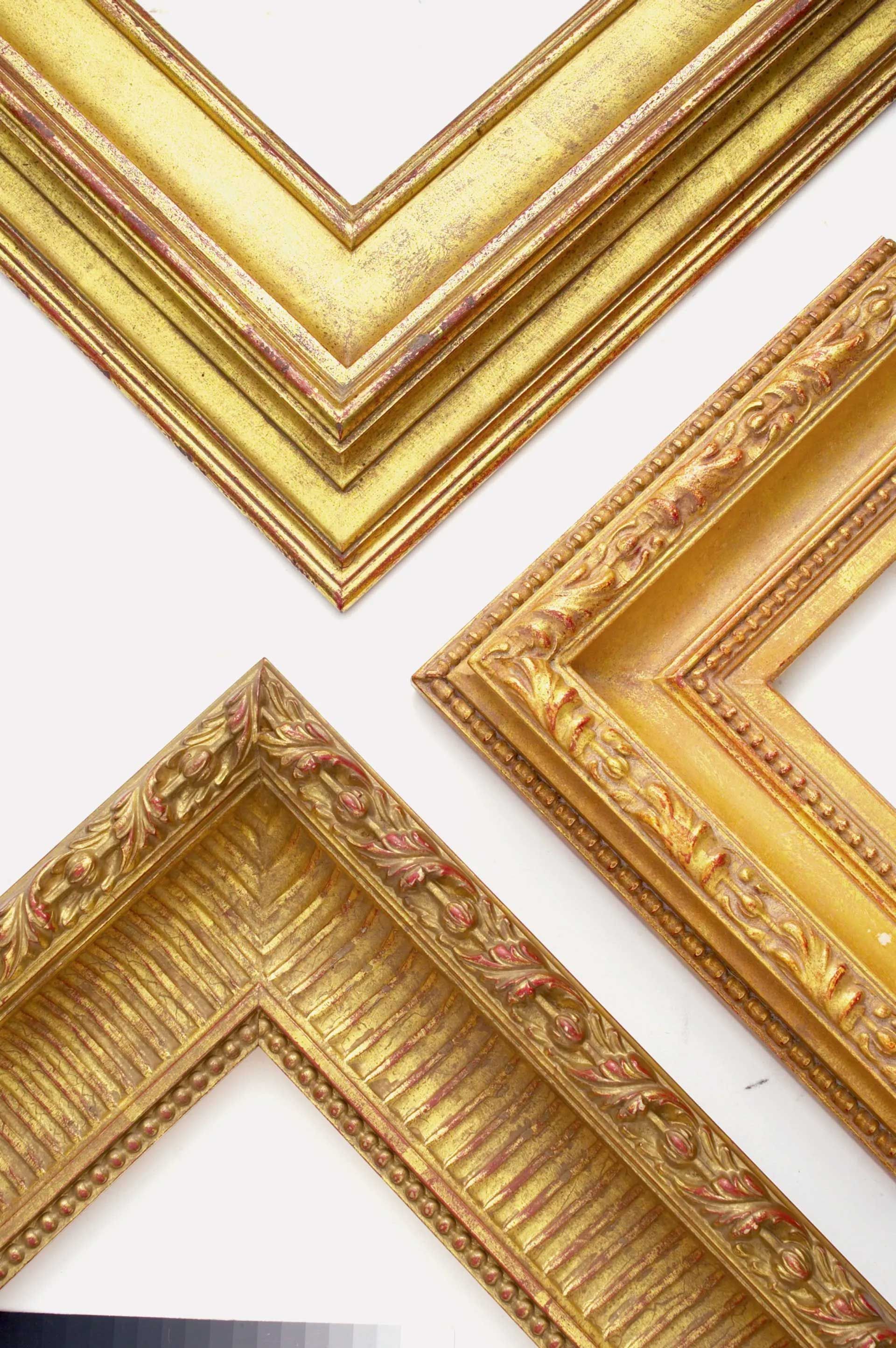 Three ornate gold-toned picture frame corners against a white background.