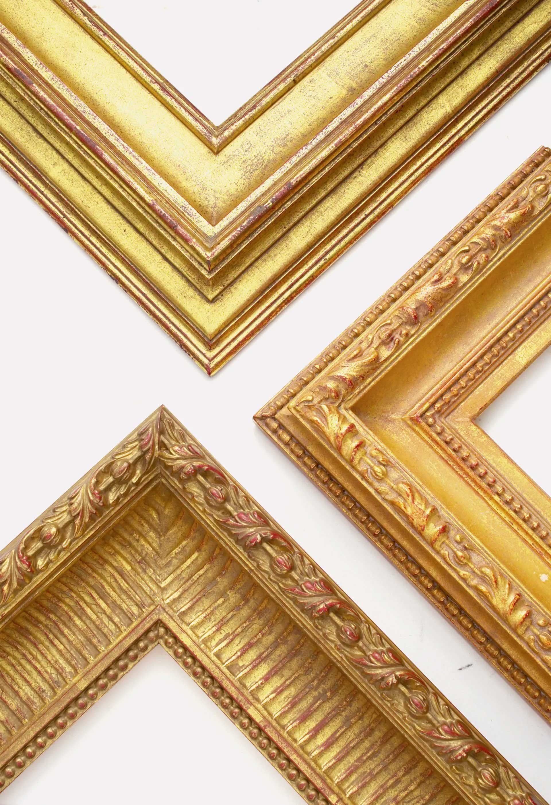 Three ornate, gold-colored picture frame corners of varying designs arranged against a plain white background.