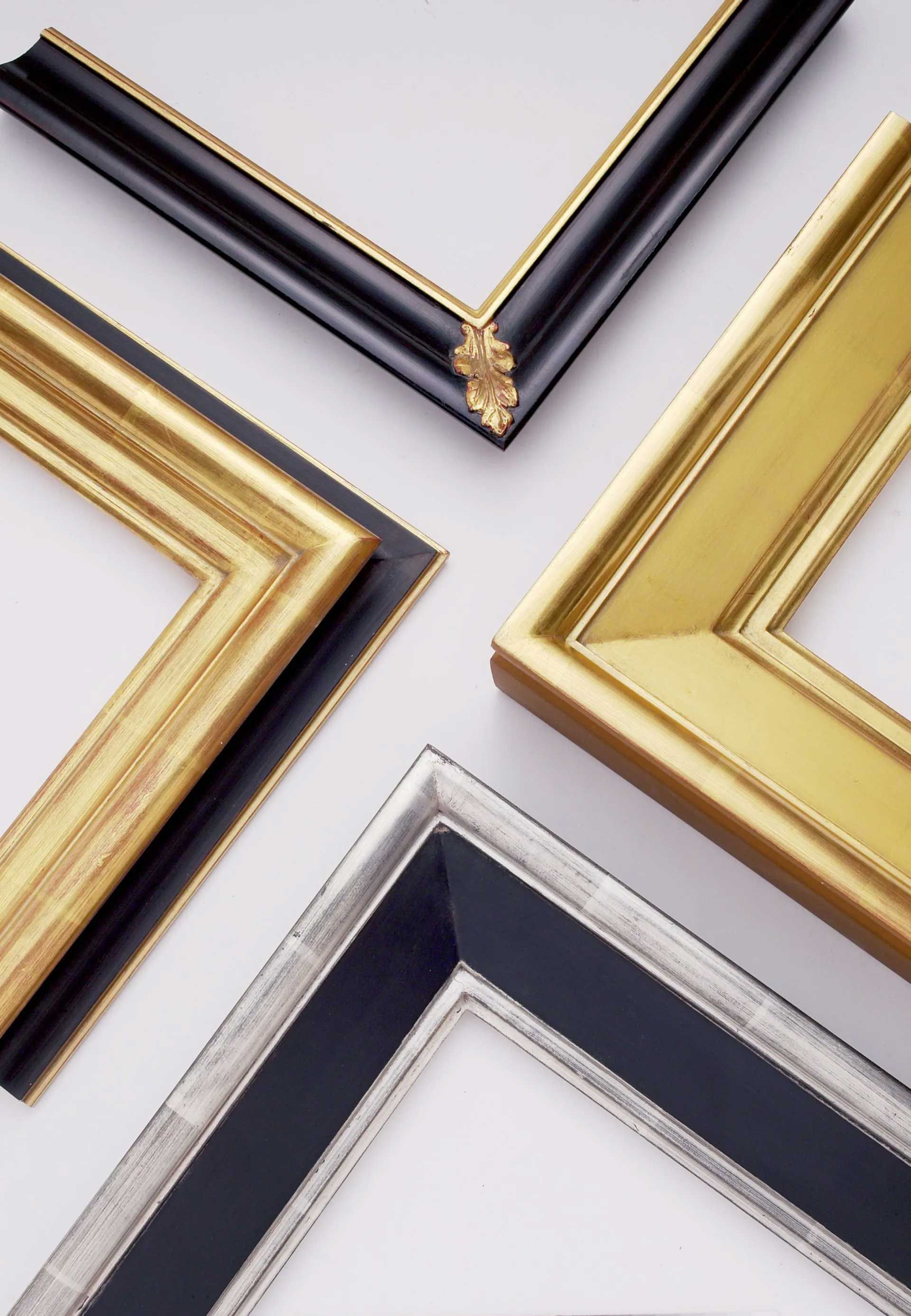 Four ornate picture frame corners in black and gold, solid gold, and black and silver, arranged against a white background.