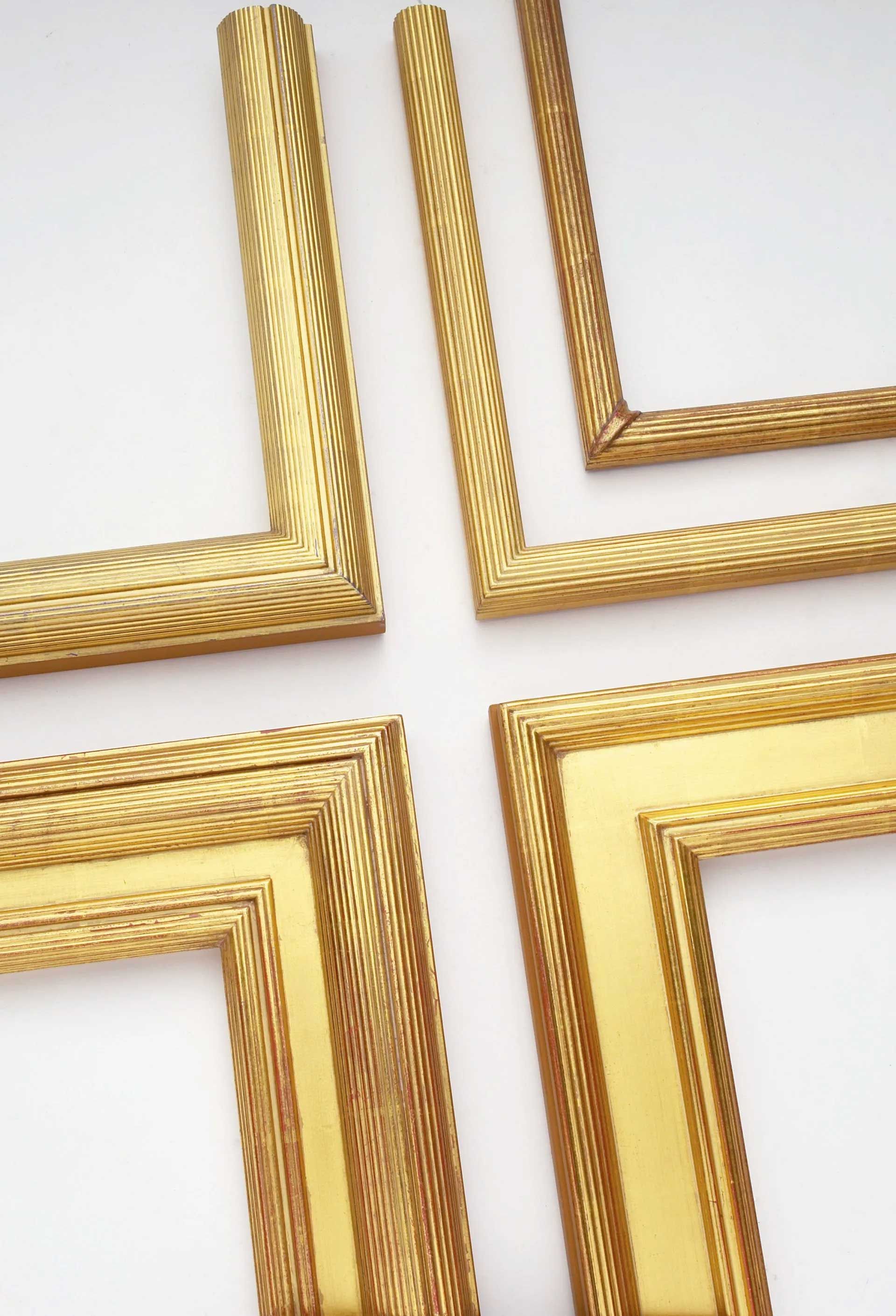 Four corner sections of ornate gold-colored picture frames arranged to form a cross against a white background.