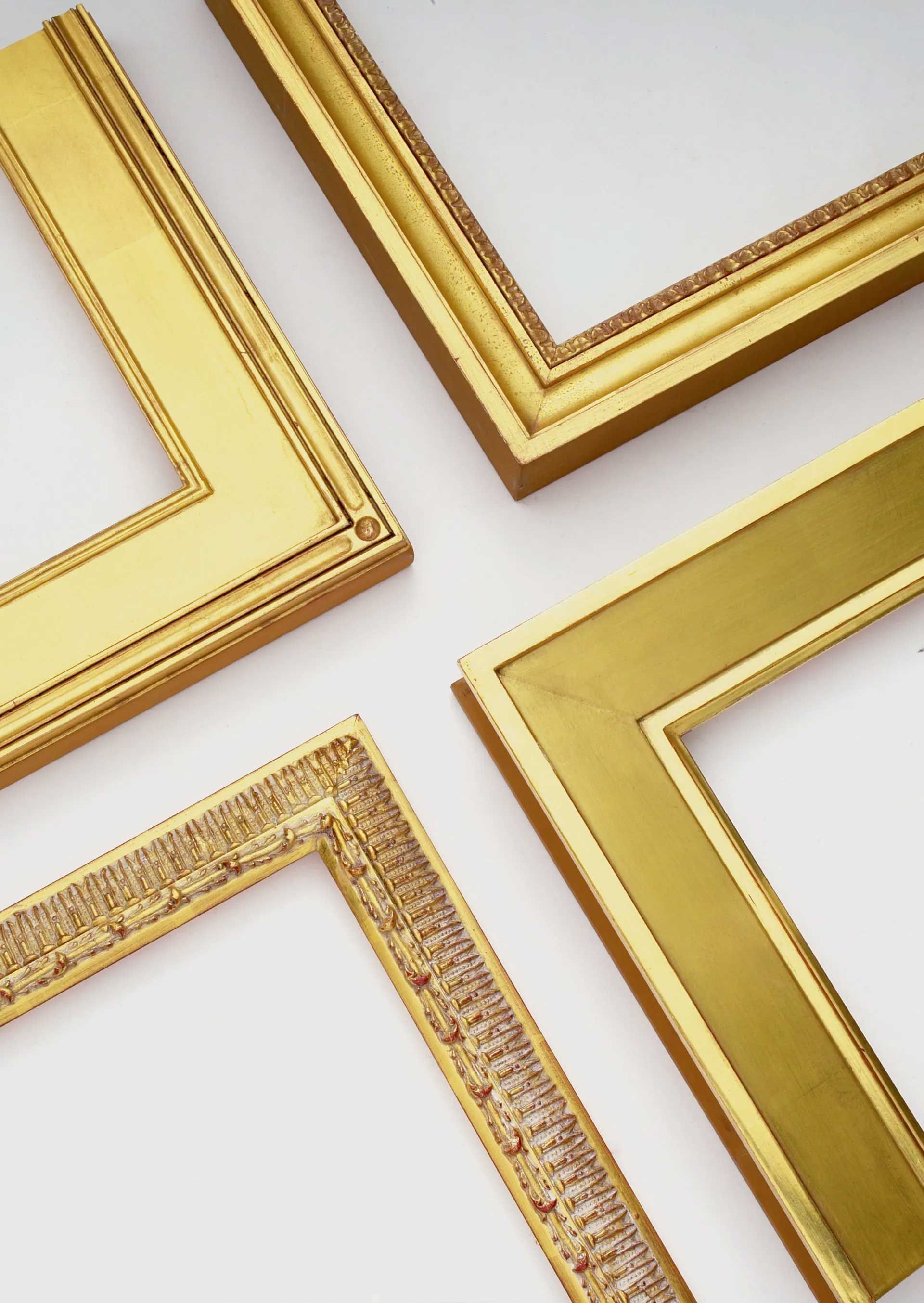 Four gold ornate picture frames arranged in a cross pattern against a plain white background.
