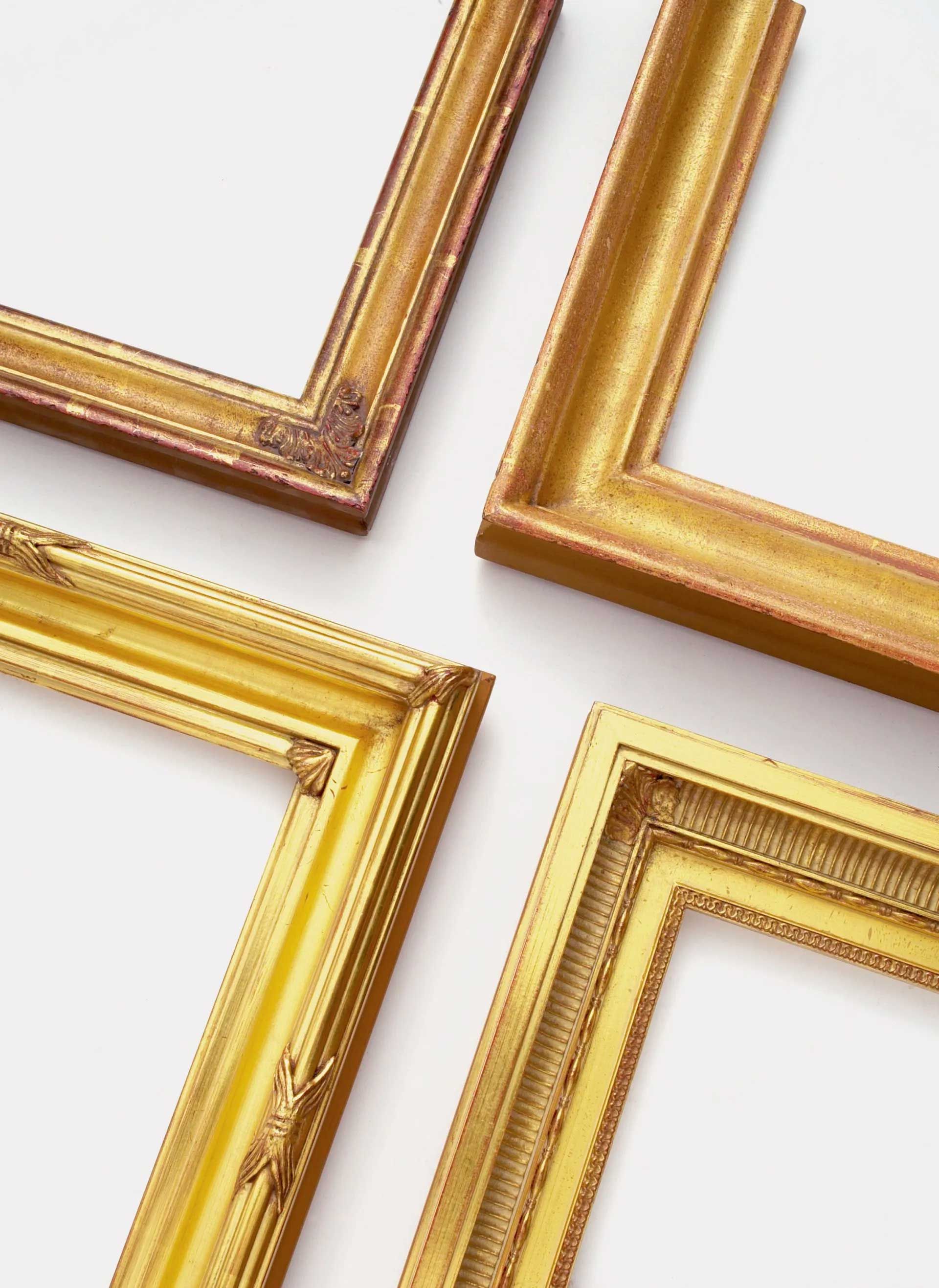 Four ornate, rectangular gold picture frames arranged to form a cross shape against a white background.