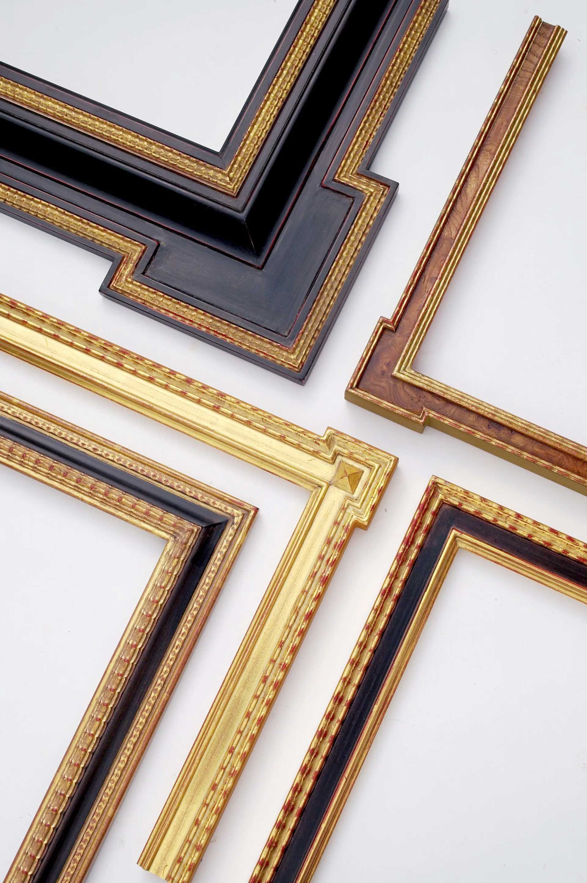 Four ornate, decorative picture frame corners in various black, gold, and wood finishes arranged on a white background.