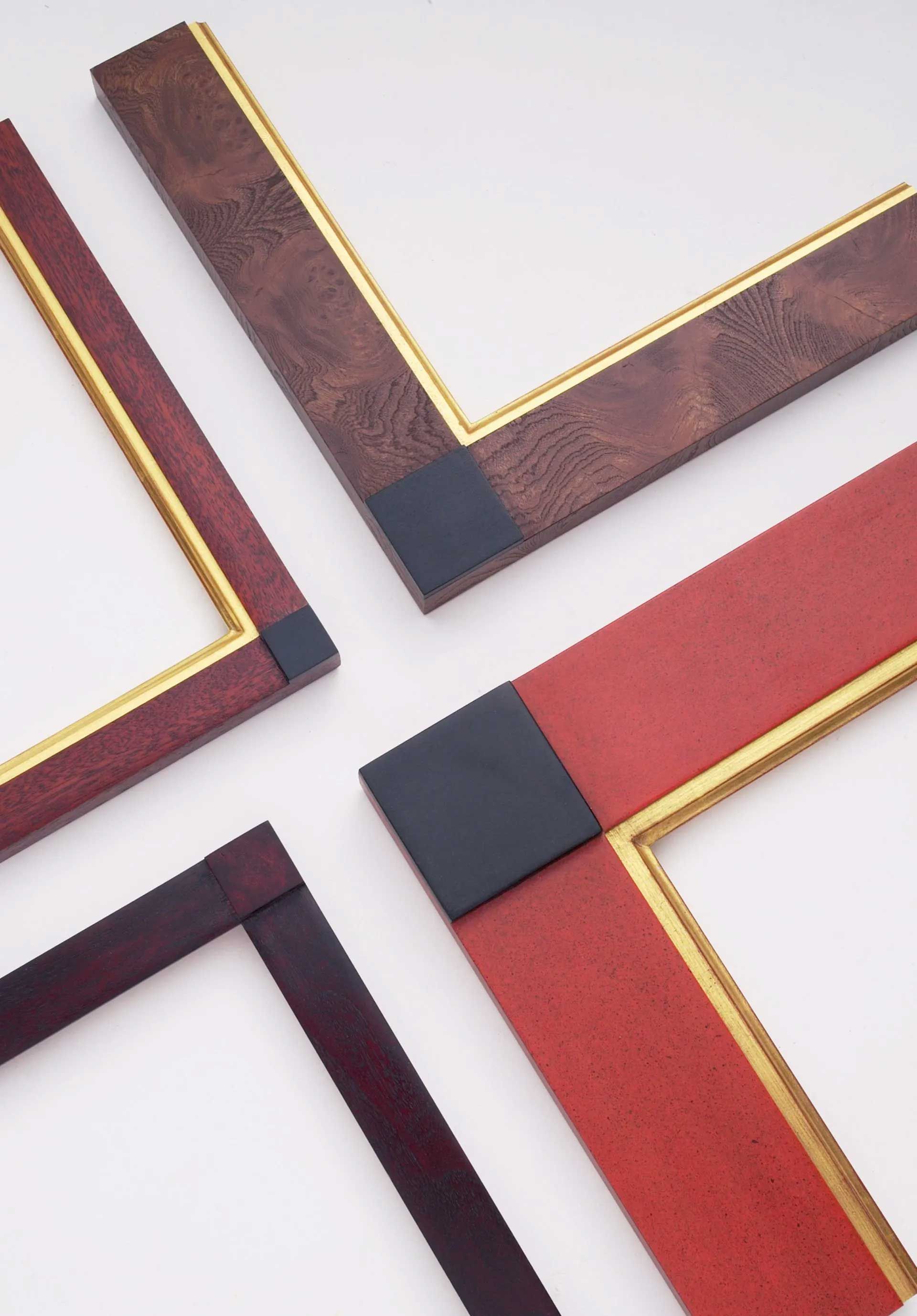 Four L-shaped picture frame corners with textured red and brown finishes, each accented with a gold inner trim.